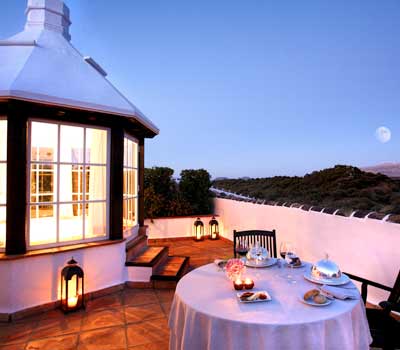 cena romanticas en azotea mesa servida para dos lamparas de fondo cielo y monte con arboles